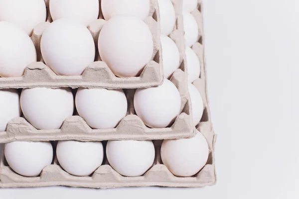 Ovos brancos de uma galinha em embalagem de cartão inofensiva em um contexto branco. 3 embalagens . — Fotografia de Stock