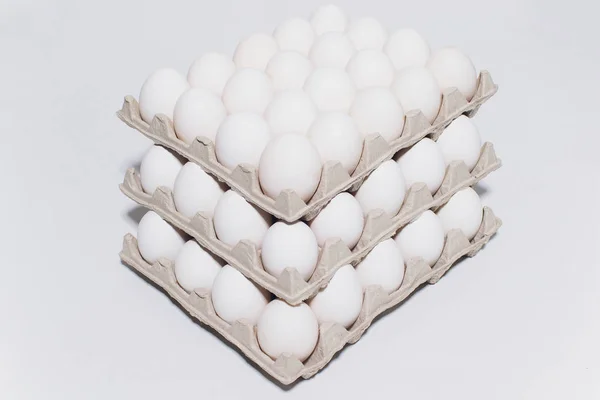 Los huevos blancos de la gallina en inofensivo, el embalaje de cartón sobre el fondo blanco. 3 paquetes . — Foto de Stock