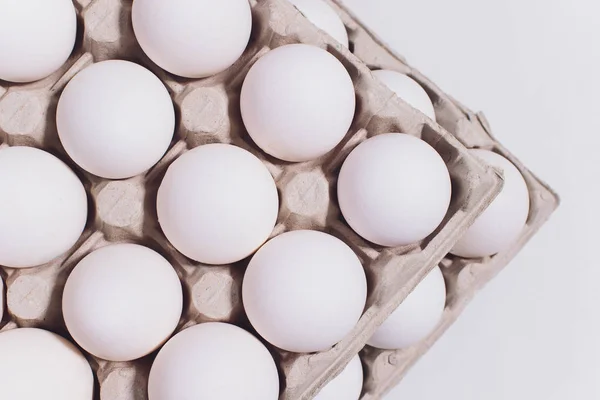 Ovos brancos de uma galinha em embalagem de cartão inofensiva em um contexto branco. 2 embalagens . — Fotografia de Stock