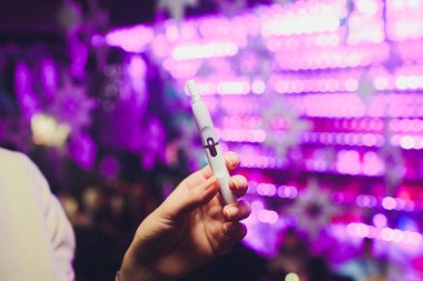Elektronik Sigara, teknoloji sigara. Tütün sistemi Iqos. Restoran bulanık arka plan üzerinde kadın el