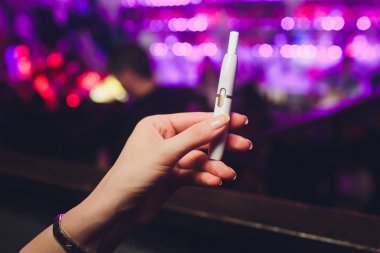 Elektronik Sigara, teknoloji sigara. Tütün sistemi Iqos. Restoran bulanık arka plan üzerinde kadın el