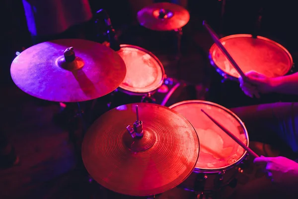 De mens bespeelt muziekpercussie-instrument met stokken close-up op een zwarte achtergrond, een muzikaal concept met de werkende drum, mooie verlichting op het podium. — Stockfoto