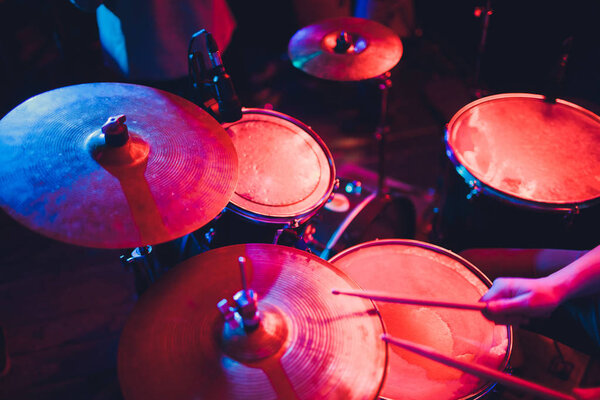 Человек играет на музыкальном ударном инструменте с палками крупным планом на черном фоне, музыкальная концепция с рабочим барабаном, красивое освещение на сцене.