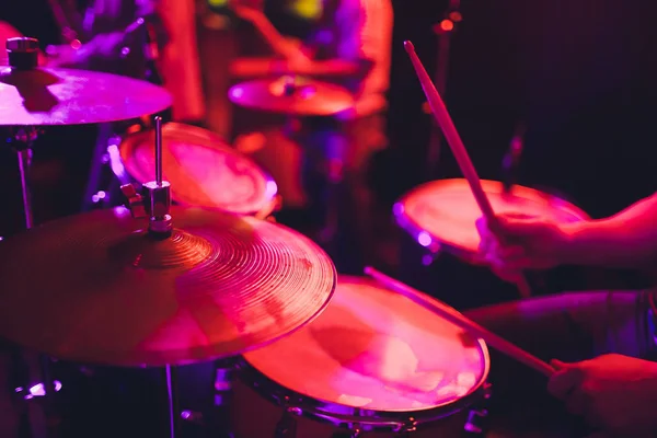 De mens bespeelt muziekpercussie-instrument met stokken close-up op een zwarte achtergrond, een muzikaal concept met de werkende drum, mooie verlichting op het podium. — Stockfoto