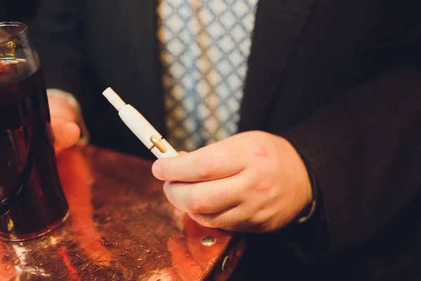 Tecnologia dei prodotti del tabacco non bruciati termicamente IQOS. Uomo che tiene la sigaretta elettronica in mano prima di fumare . — Foto Stock