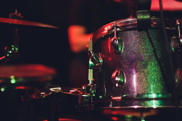 De mens bespeelt muziekpercussie-instrument met stokken close-up op een zwarte achtergrond, een muzikaal concept met de werkende drum, mooie verlichting op het podium. — Stockfoto