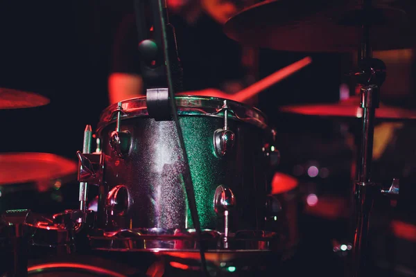 De mens bespeelt muziekpercussie-instrument met stokken close-up op een zwarte achtergrond, een muzikaal concept met de werkende drum, mooie verlichting op het podium. — Stockfoto