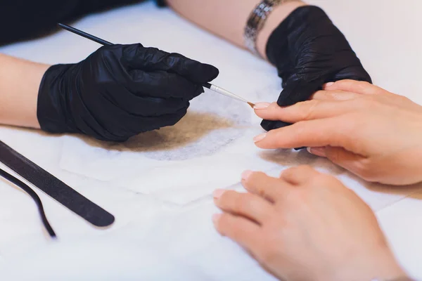 Hardware Manicure using electric device machine. procedure for the preparation of nails before applying nail polish. Hands of Manicurist in black gloves and Nails of Client. Woman In Beauty Salon.