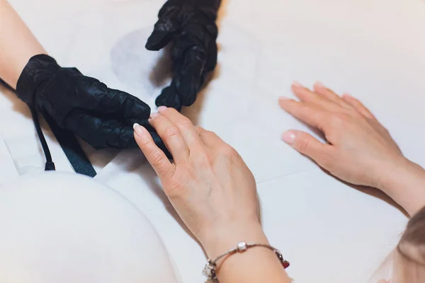 Hardware Manicure using electric device machine. procedure for the preparation of nails before applying nail polish. Hands of Manicurist in black gloves and Nails of Client. Woman In Beauty Salon.