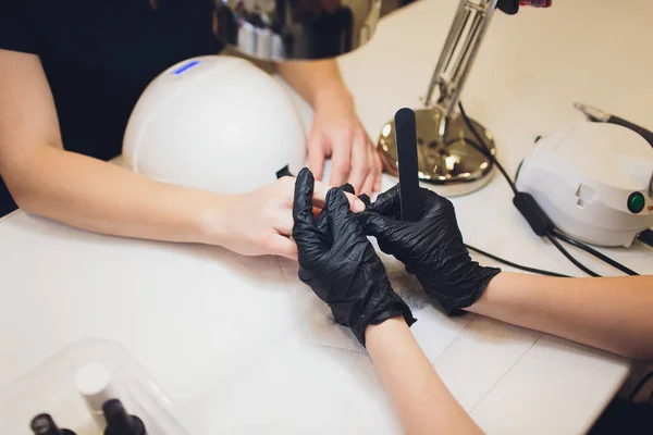 Hardware Manicure using electric device machine. procedure for the preparation of nails before applying nail polish. Hands of Manicurist in black gloves and Nails of Client. Woman In Beauty Salon.