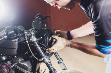 Adam bisikleti onariyor. Onun garajına yakın motosiklet tamir emin genç adam. Far içinde yedek lamba