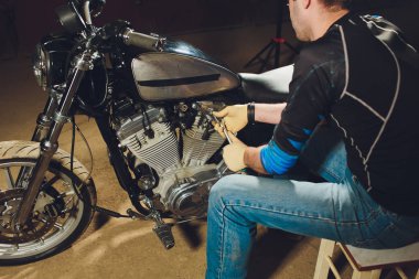 Adam bisikleti onariyor. Onun garaj yakınında motosiklet tamir emin genç adam.