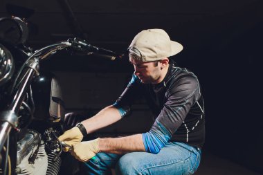 Adam bisikleti onariyor. Onun garaj yakınında motosiklet tamir emin genç adam.