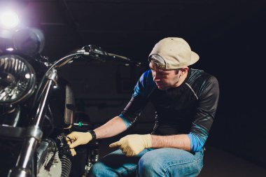 Adam bisikleti onariyor. Onun garaj yakınında motosiklet tamir emin genç adam.