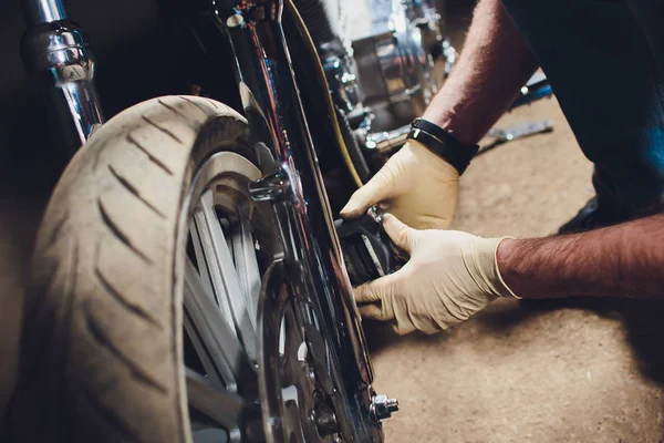 Hombre arreglando bicicleta. Joven confiado reparando motocicletas cerca de su garaje. pinza, reemplazo de pastillas de freno — Foto de Stock