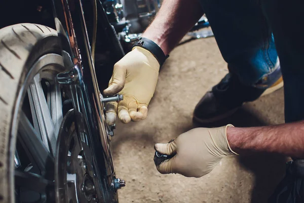 Hombre arreglando bicicleta. Joven confiado reparando motocicleta cerca de su garaje . — Foto de Stock