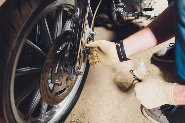 Hombre arreglando bicicleta. Joven confiado reparando motocicleta cerca de su garaje . — Foto de Stock