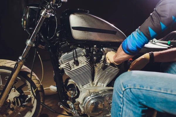 Mann repariert Fahrrad. Selbstbewusster junger Mann repariert Motorrad in der Nähe seiner Garage. — Stockfoto