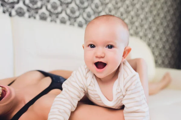 Een moeder en baby kind op een witte bed. — Stockfoto