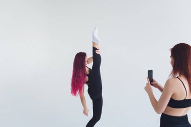 Kız spor fitness yoga pilates carimat egzersizleri jimnastik smartphone mat carimat egzersiz bej renkli arka plan üzerinde.