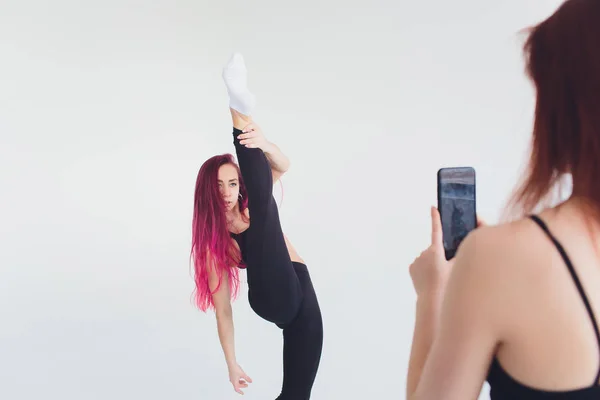 Lány sport fitness jóga pilates carimat gyakorlatok torna smartphone mat carimat gyakorlat egy bézs háttérrel. — Stock Fotó