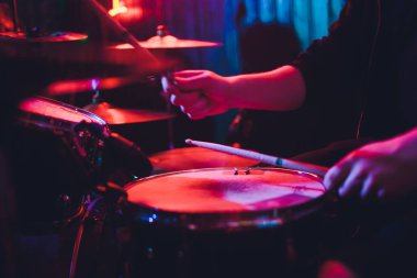 Davulcu sahnede konserde davul çalıyor. Müzik şovu. Kulüpte parlak sahne ışıkları, ellerinde davul sopaları..