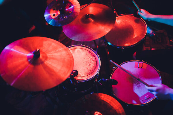 Baterista tocando batería en concierto en el escenario. Espectáculo musical. Iluminación de escena brillante en el club, palos de tambor en las manos . — Foto de Stock