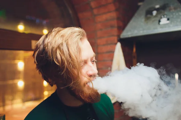 A srác dohányzik, exhales füst. Gőz elektronikus cigaretta. Portré egy fiatalember a füstöt. A könnyű, az arcon a fény foltok által a gőz-örvények. — Stock Fotó