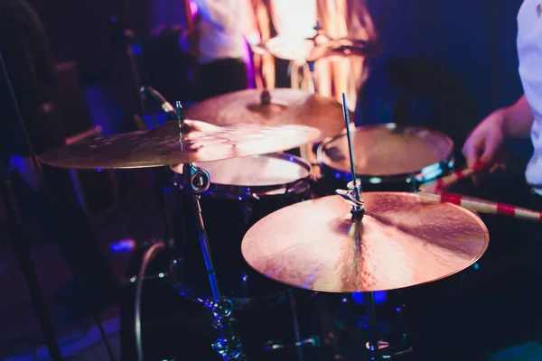 Schlagzeuger mit einem Schlagstock in der Hand, der auf dem Schlagzeug auf der Bühne auf schwarzem Hintergrund spielt. — Stockfoto