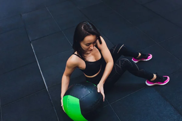 Gespierde vrouw doet intense core workout in Gym. Sterke vrouwelijke doen kern oefening op fitness mat met geneeskunde bal in Health Club. — Stockfoto