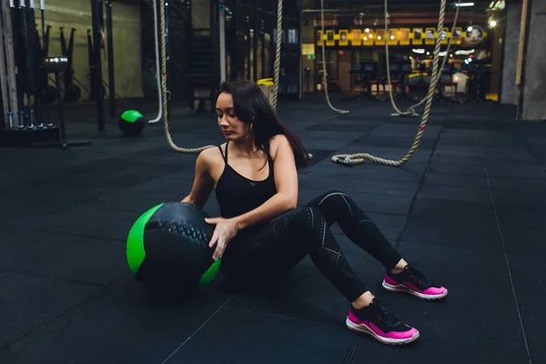 Gespierde vrouw doet intense core workout in Gym. Sterke vrouwelijke doen kern oefening op fitness mat met geneeskunde bal in Health Club. — Stockfoto