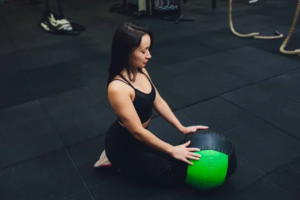 Muskularna kobieta robi intensywny rdzeń treningu w siłowni. Silna kobieta robi podstawowe ćwiczenia na mat fitness z medycyny piłkę w klubie zdrowia. — Zdjęcie stockowe