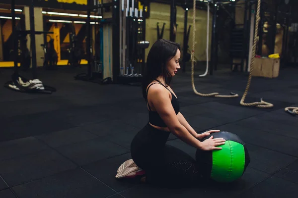 Gespierde vrouw doet intense core workout in Gym. Sterke vrouwelijke doen kern oefening op fitness mat met geneeskunde bal in Health Club. — Stockfoto