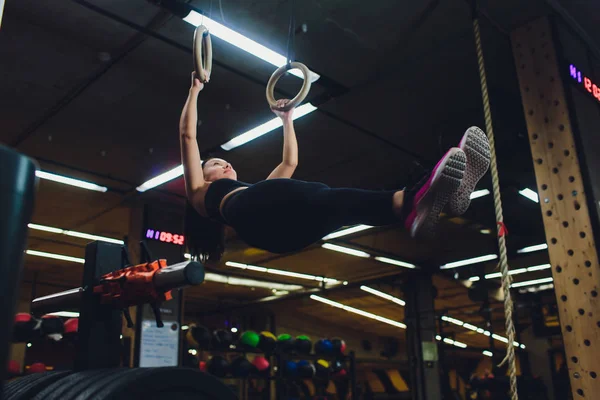 Молодая спортсменка, занимающаяся спортом на гимнастических кольцах в спортзале . — стоковое фото