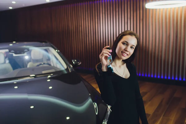 Conductora sosteniendo llaves del auto. Sala de exposición de coches . —  Fotos de Stock