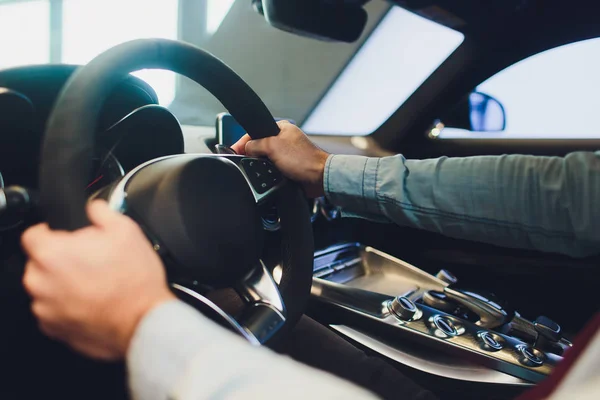 Empresario que conduce un coche moderno de lujo en la ciudad. Primer plano mans mano en el volante del coche . —  Fotos de Stock