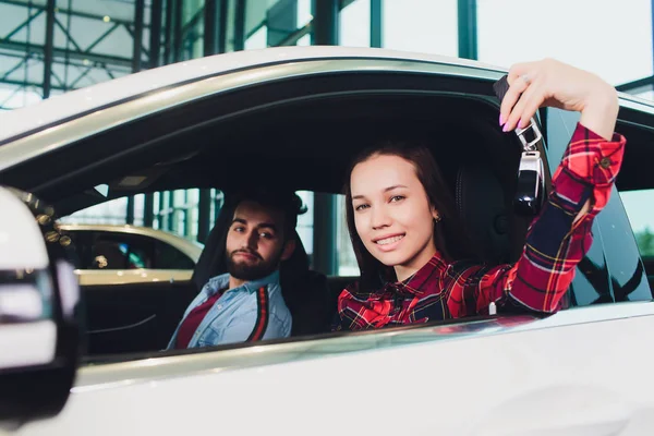 Foto de una joven sonriente mujer de raza mixta sentada dentro de su nuevo coche y sosteniendo la llave. Concepto de alquiler de coches . —  Fotos de Stock