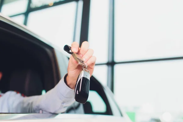 Pohledný muž středního věku ukazující na auto klíč v novém autě. — Stock fotografie