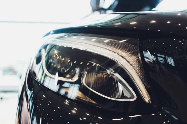 Close-up koplampen voorkant uitzicht, zwarte kleur auto in de kamer. — Stockfoto