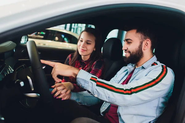 Visitando concesionario de coches. Hermosa pareja está hablando y sonriendo mientras está sentado en su nuevo coche . —  Fotos de Stock