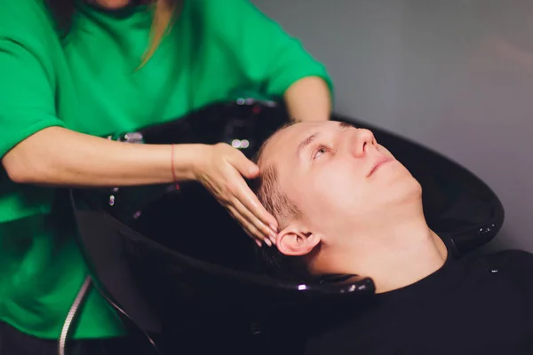 Młody człowiek myje głowę w salonie fryzjerskim. — Zdjęcie stockowe