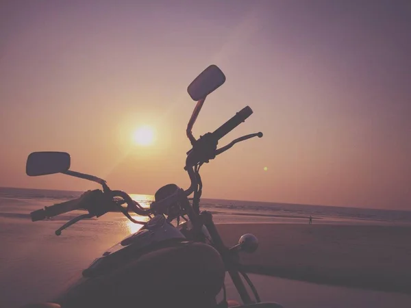 Motorcycle.photo Motorrad bei Sonnenuntergang an einem Sandstrand in Goa, Indien. — Stockfoto