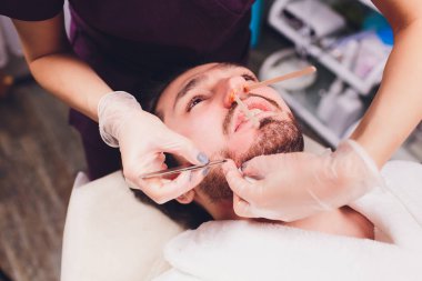 Epilasyon. Mans kanepedeki kozmetolojide sugaring epilationsy sarı renk, yüz. burun içinde epilasyon.