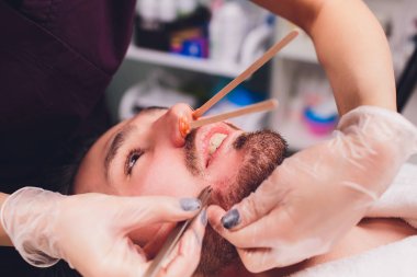 Epilasyon. Mans kanepedeki kozmetolojide sugaring epilationsy sarı renk, yüz. burun içinde epilasyon.