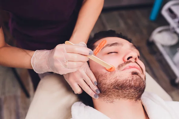 Remoção de cabelo. Mans rosto açúcar epilations barba aparar, cor amarela, em cosmetologia no sofá . — Fotografia de Stock