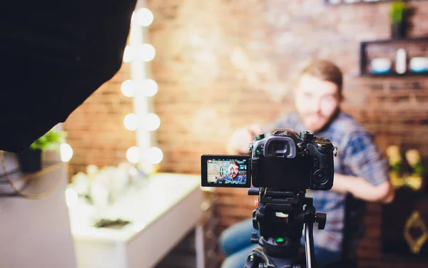 Jovem blogueiro com gravação de vídeo contra fundo de parede de tijolo fala sobre procedimentos de cosmetologia e produtos cosméticos . — Fotografia de Stock