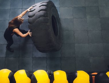 Fit kadın atlet büyük bir lastik ile dışarı çalışma, tornalama ve spor salonunda taşımak. kadın büyük lastik ile egzersiz.
