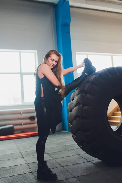 Fit női sportoló dolgozott ki egy hatalmas gumiabroncs, esztergálás és folytatni az edzőteremben. nő gyakorló nagy gumiabroncs. — Stock Fotó