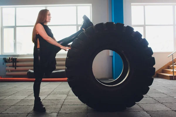 Fit női sportoló dolgozott ki egy hatalmas gumiabroncs, esztergálás és folytatni az edzőteremben. nő gyakorló nagy gumiabroncs. — Stock Fotó