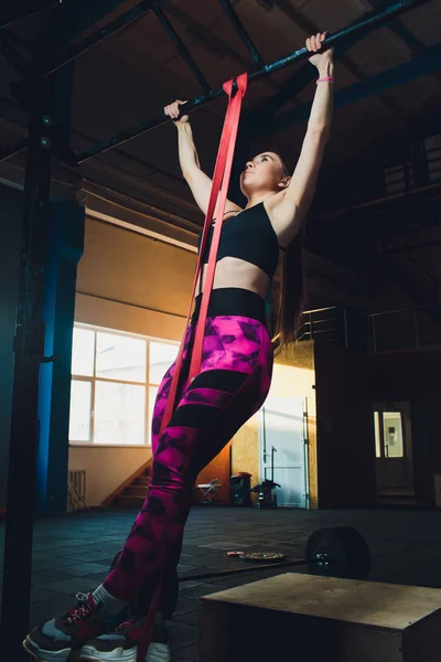 Widok z boku sportowy dziewczyna ćwiczenia z elastycznego pasma oporu na zewnątrz. — Zdjęcie stockowe